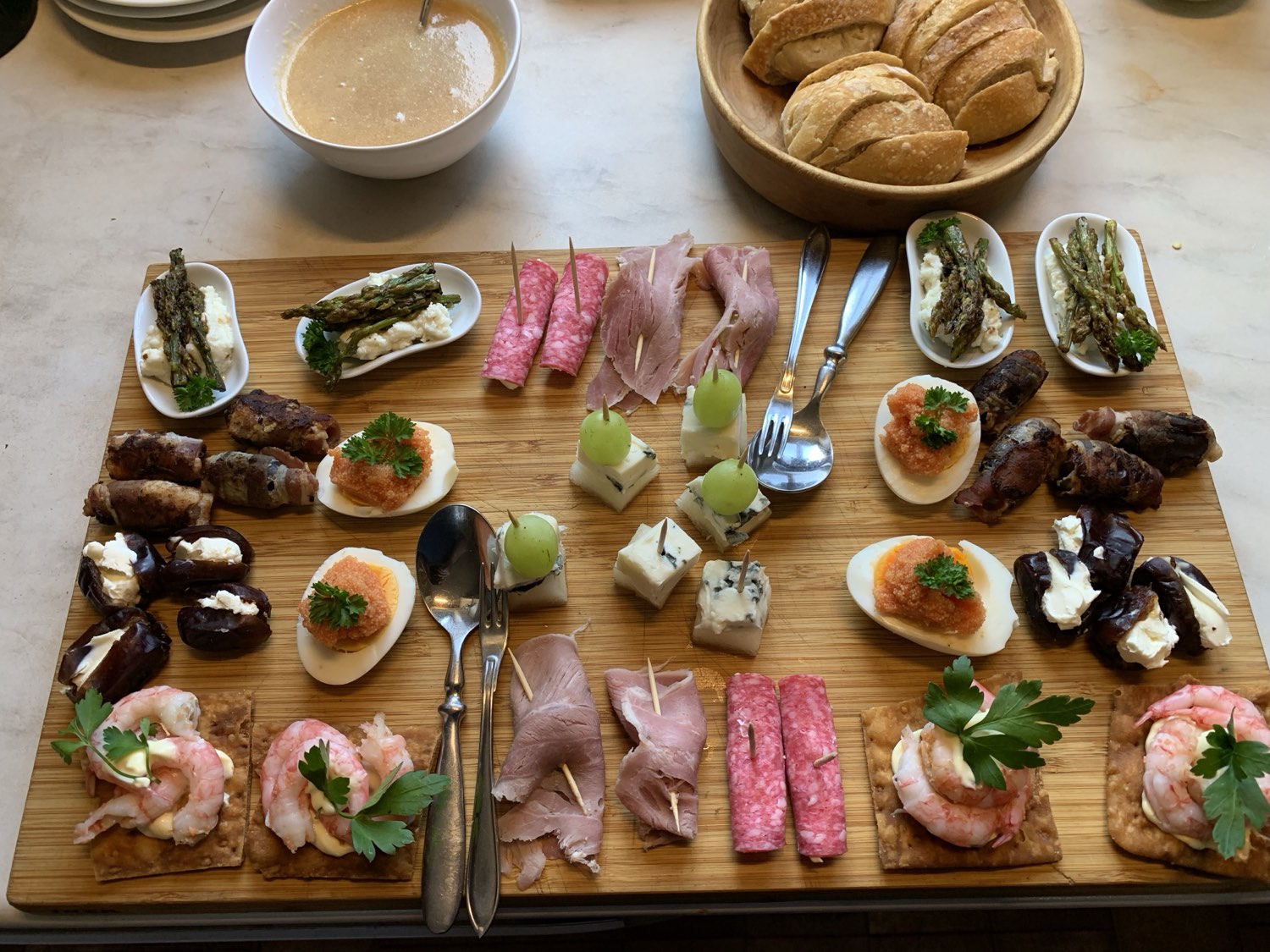 A wooden board laid with home-made charcuterie, eggs, pickles and bread