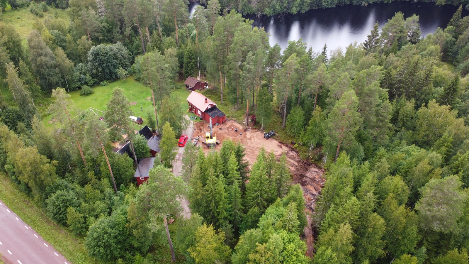 Aerial view of the house and outbuildings in a clearing beside a dark forest river